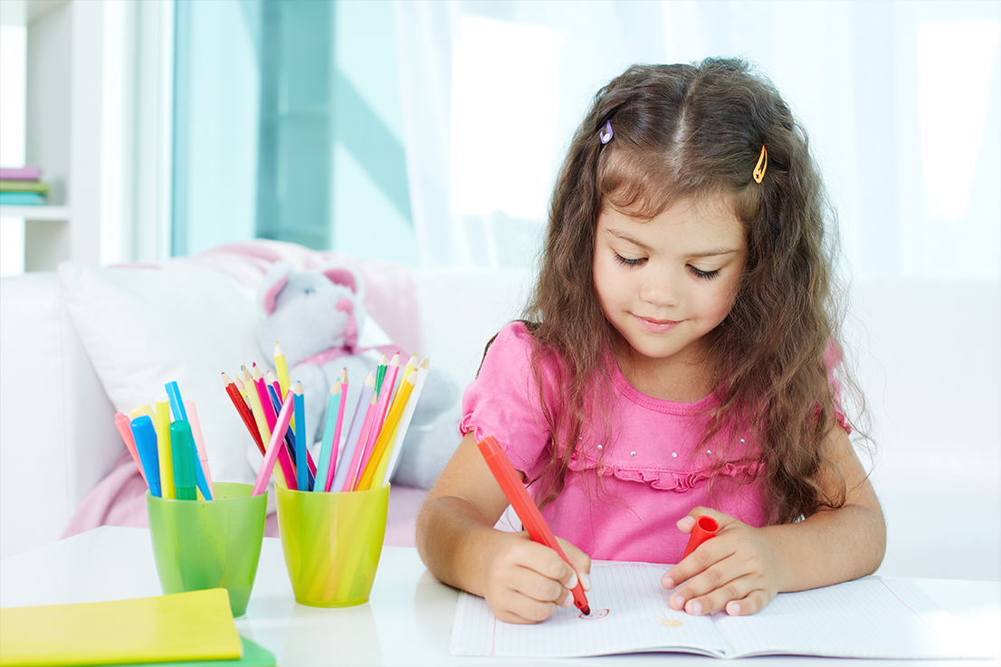 Portrait of lovely girl drawing with colorful pencils