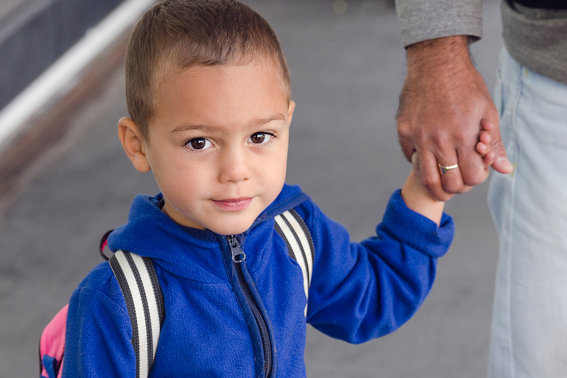 Portrait of  child toddler, boy or girl, holding a hand of father.